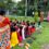 A group of women and girls sitting on the ground outdoors in North Bengal, India, attentively listening to a literacy talk.