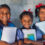 Indian rural schoolgirls holding books standing in school.